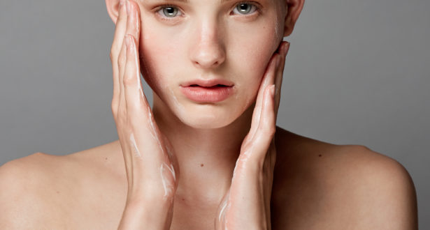 girl putting on facial moisturizer