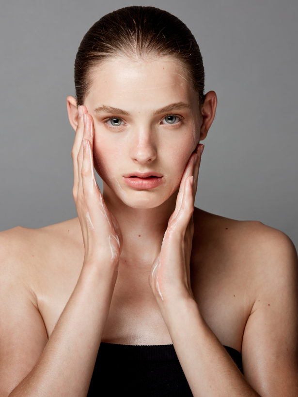 girl putting on facial moisturizer